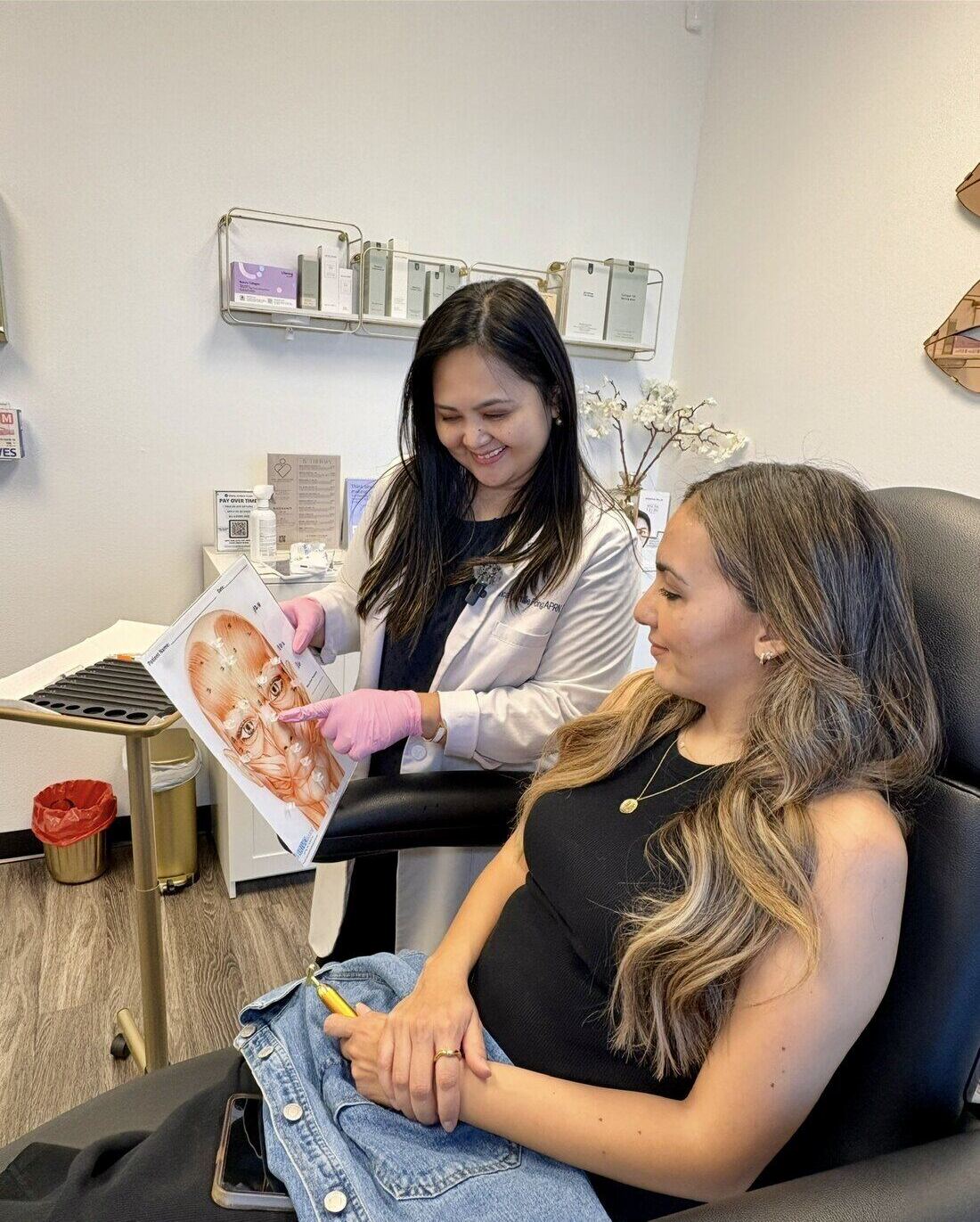 Bianca Fong, nurse practitioner, showing a client a diagram of the facial nerves while the client sits in the treatment chair at Blanqa Medspa.